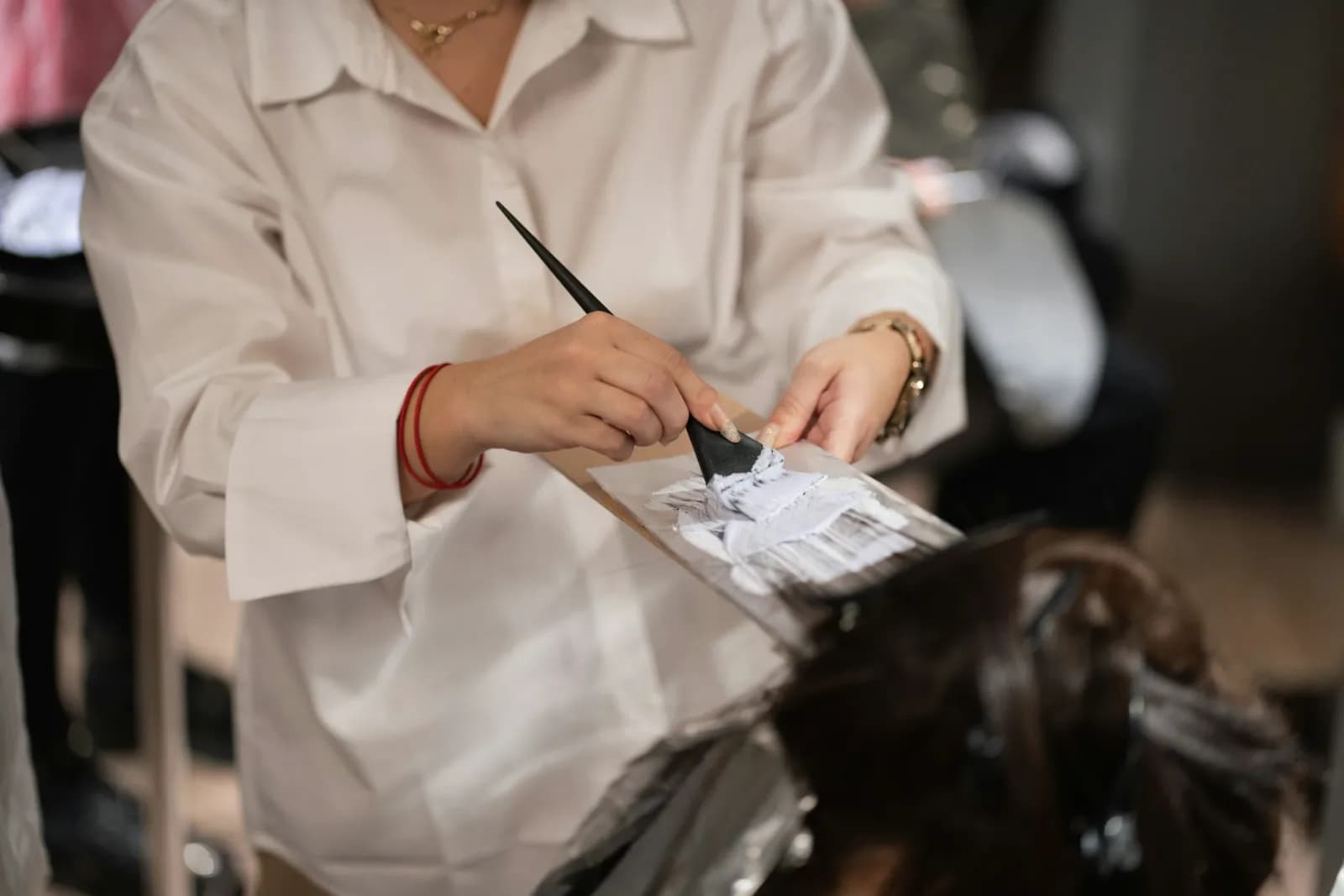 A colourist brushing colour onto a section of hair laid over foil.